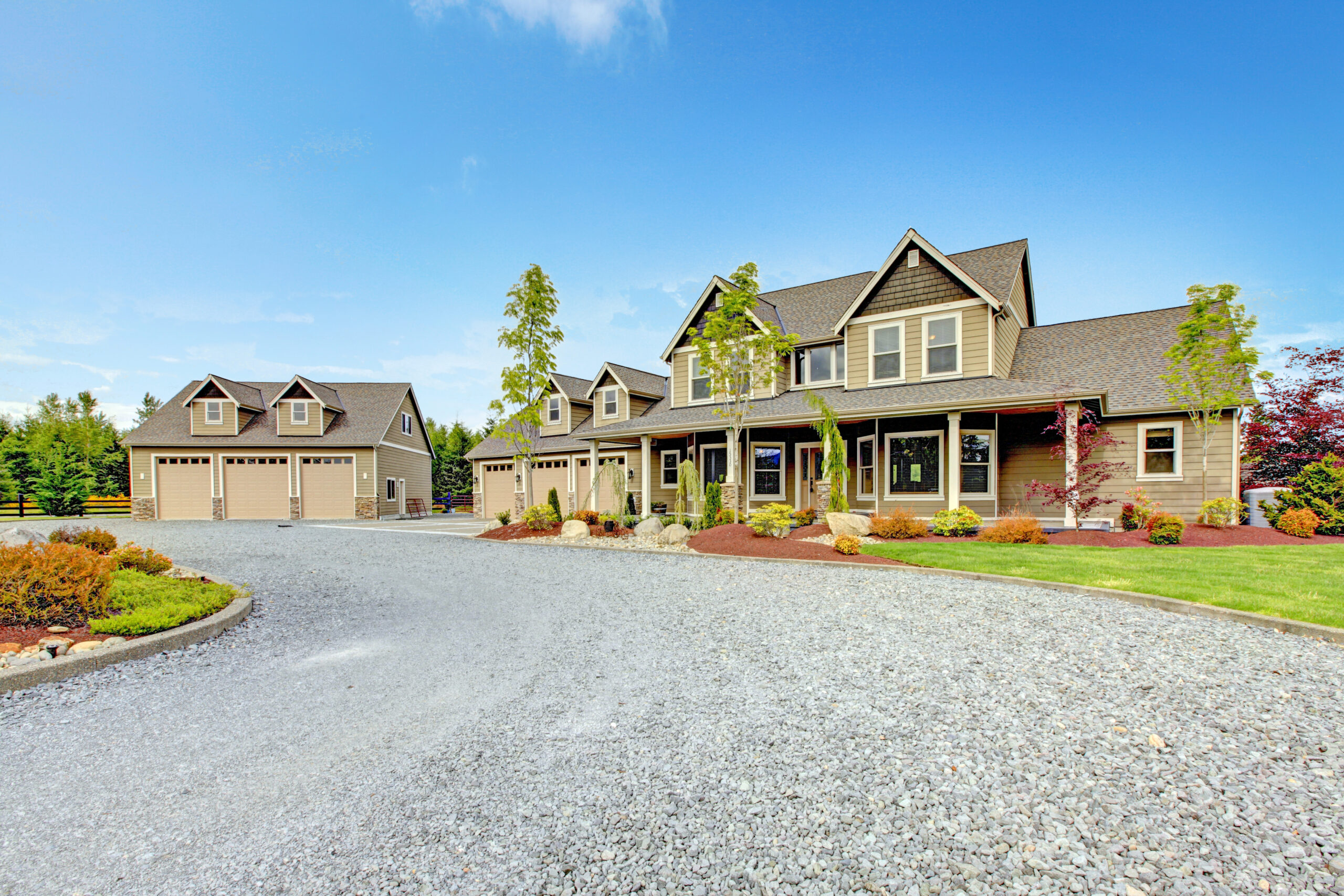 Large farm country house with gravel driveway and green landscape.