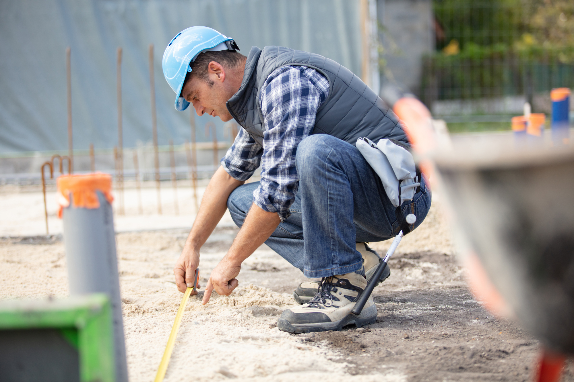 construction worker measuring foundations at site